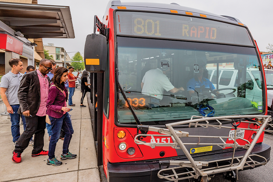 Group of men and women getting on red public bus.