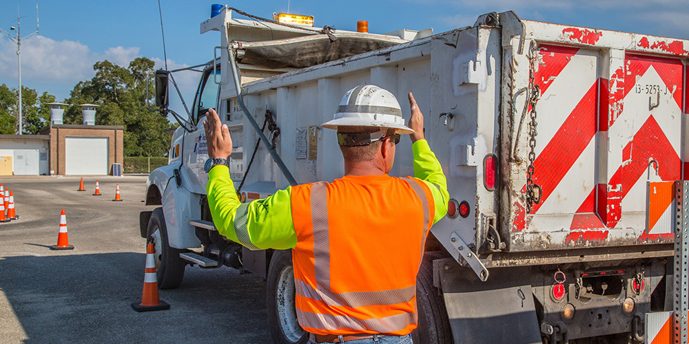 Man in PPE backs up truck