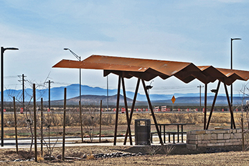 View of a picnic arbor with folded roof that mimics silhouette of distance mountains
