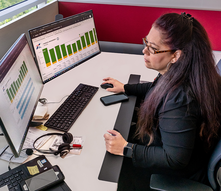 Worker at desk looking at graphics on computer monitor