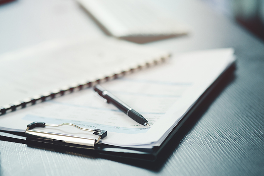 Clipboard with pen on desktop