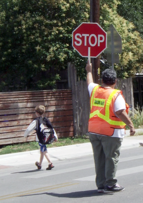 Niño cruzando la calle con guardia de cruce