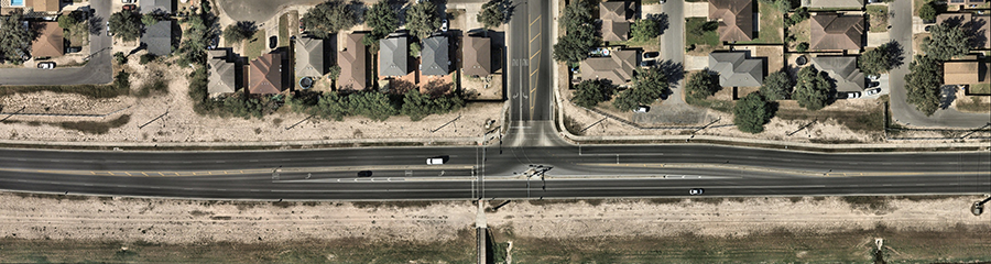 Aerial view of a Continuous Green‑T (CGT) intersection at Bicentennial Boulevard and Lark Boulevard, showing a three‑leg layout where the major roadway carries uninterrupted through traffic while the side street connects via channelized turn movements.