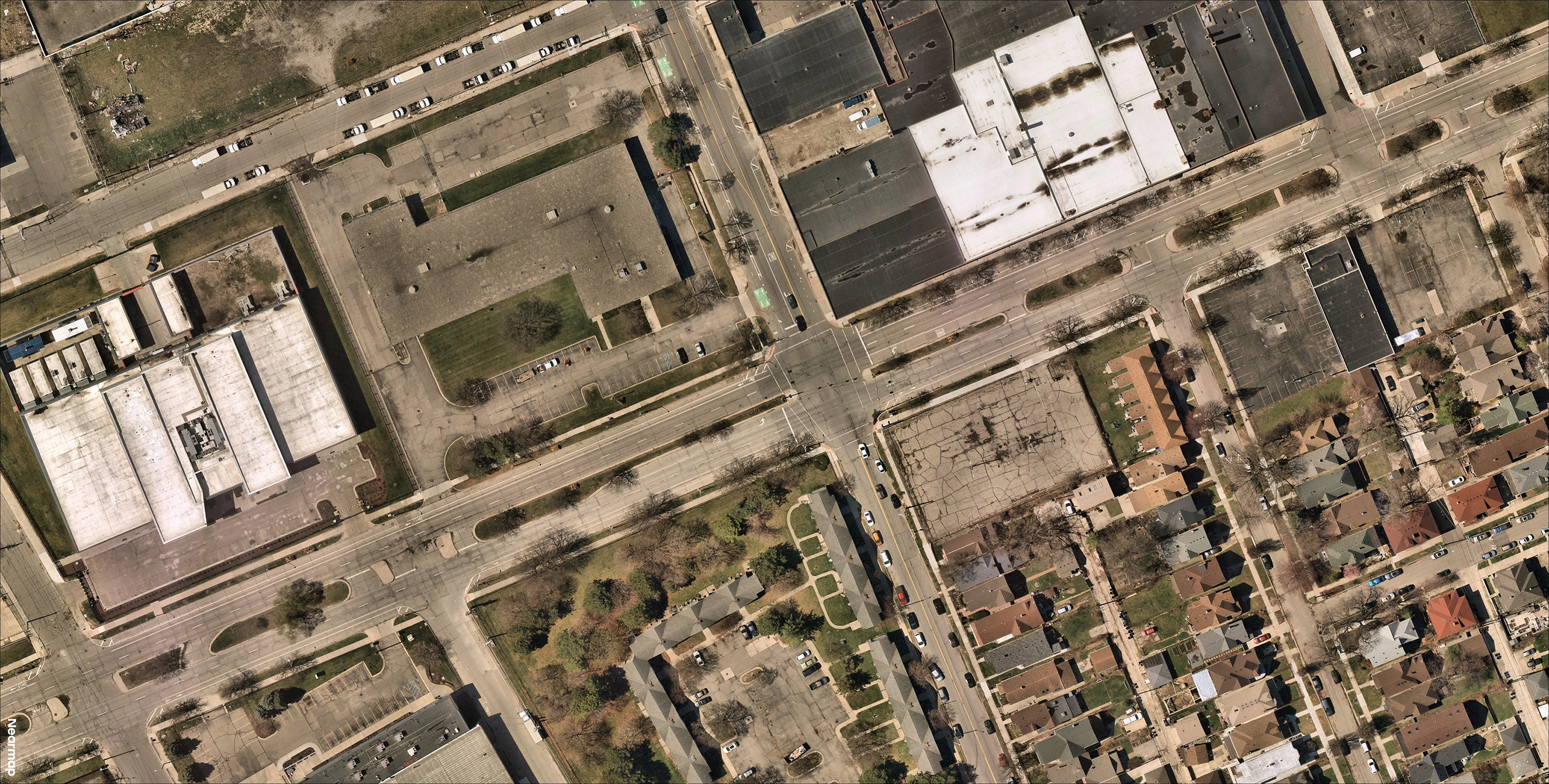 Fotografía aérea que muestra una intersección urbana de MUT con edificios, calles y vehículos aparcados circundantes. La imagen destaca el flujo visible de tráfico a través de la intersección.