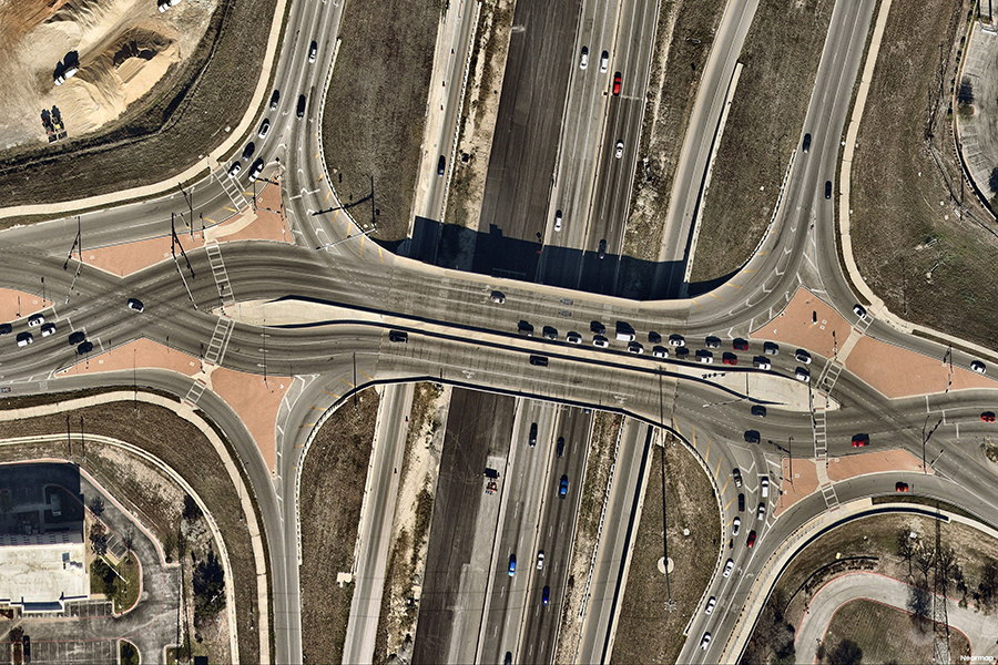 Vista aérea de un enlace en diamante divergente con el tráfico cruzando brevemente a la izquierda entre rampas y una carretera dipartida.