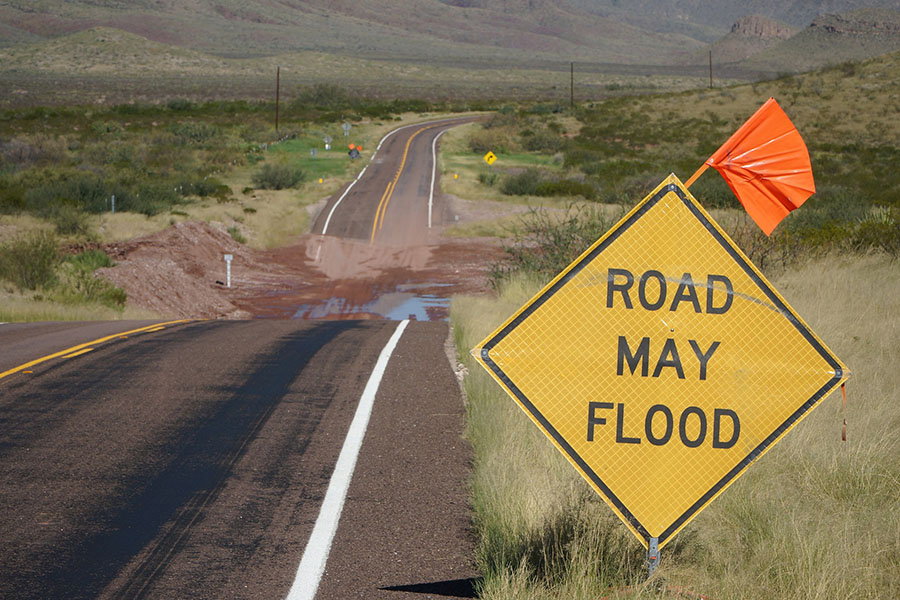 Sign warning "Road May Flood" on a two-land, rural road with flooding in Texas. 