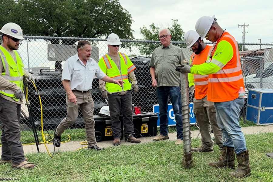 TxDOT staff work with representatives from a vendor to use a rapid-installation sign stub known as a ground screw. 
