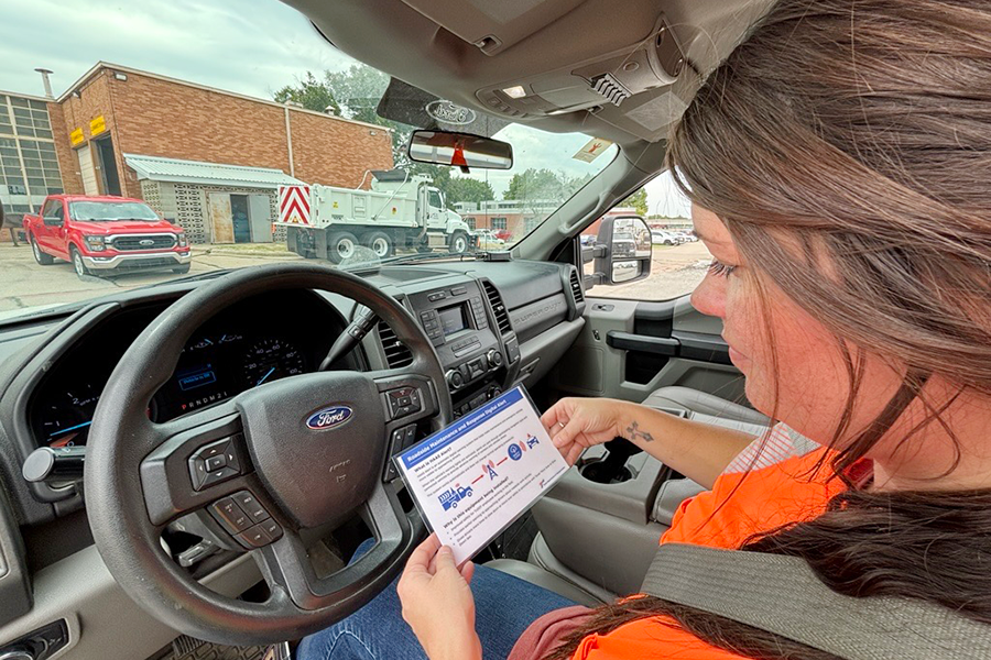 Kelcee Ivy of TxDOT's Dallas District Fleet Operations holds a card introducing the in-vehicle digital safety alert device installed in maintenance and response vehicles in the Dallas District.