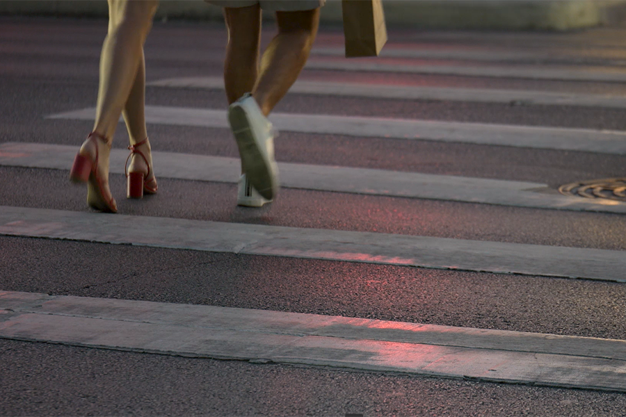 People cross the street at night using a crosswalk.