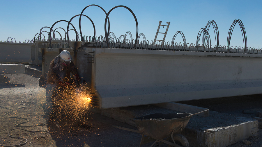 construction worker welding steel beam with sparks