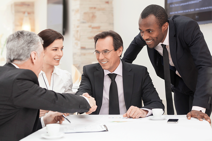 People smiling and shaking hands at a meeting.