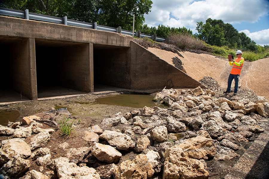Bridge inspector takes photos of a culvert in the Tyler District.
