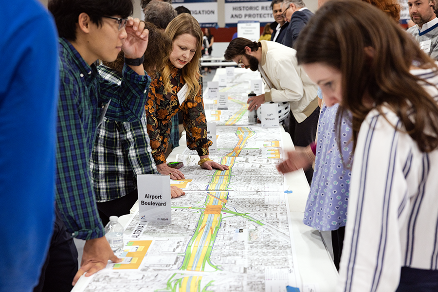 crowd gathers around tables with map images of ih35 project 