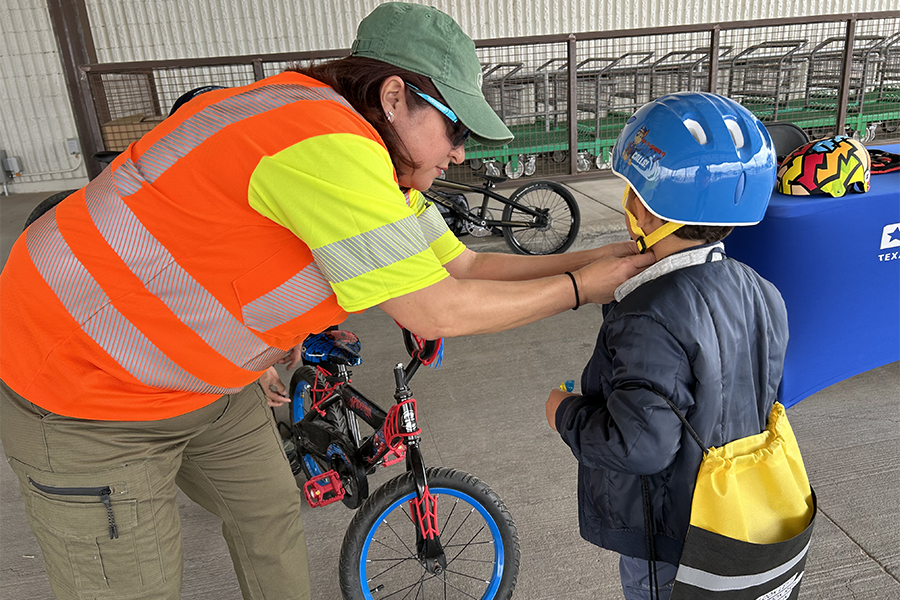 TxDOT employee checks a child's bicycle helmet