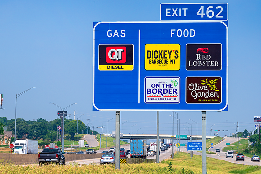 Business logos on roadsign near highway