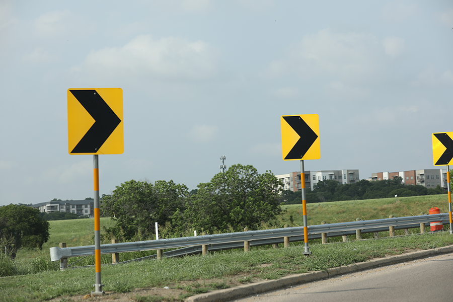Directional signs on the side of the road indicating a curve in the roadway.