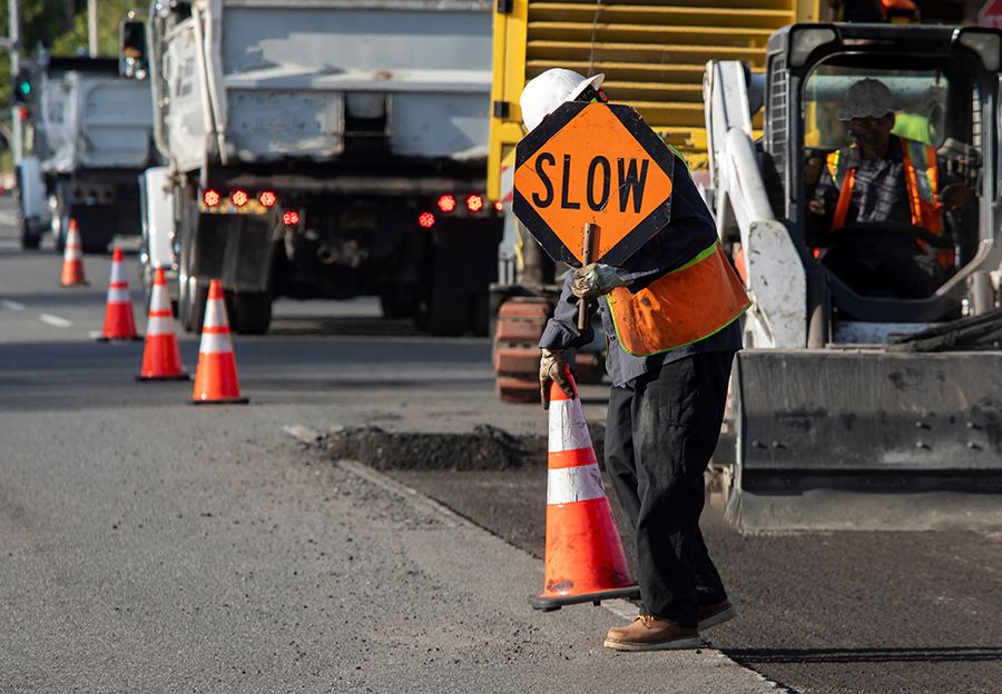 Trabajador de la construcción de carreteras sosteniendo un cartel de desaceleración