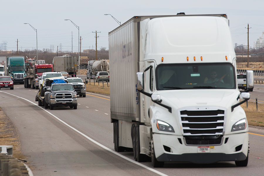 White freight truck leading other vehicles on highway. 