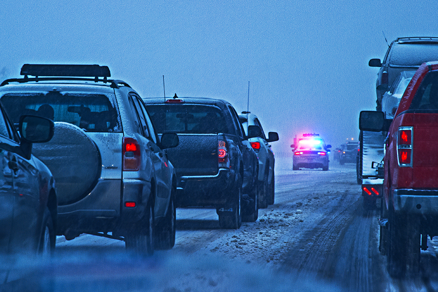 Coches en la carretera cubierta de nieve, señal de advertencia de tráfico.