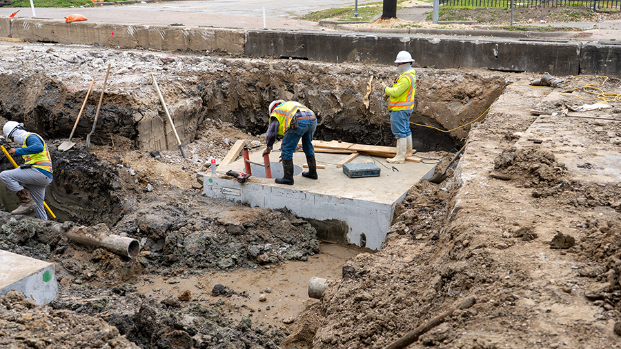 Equipos de instalación de alcantarillado pluvial alrededor de la alcantarilla en St. Emanuel y Pierce St.