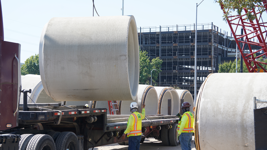Crews move seven-foot-diameter storm sewer pipe off truck