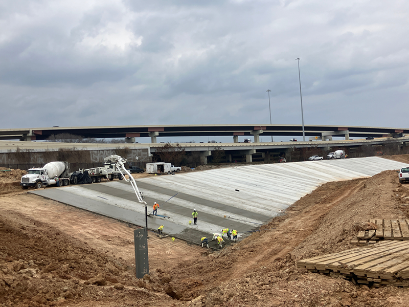 Crews pour concrete to support the sides of the detention pond