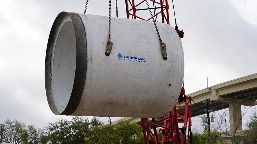 Crane lifts 8-foot diameter storm sewer pipe from the ground