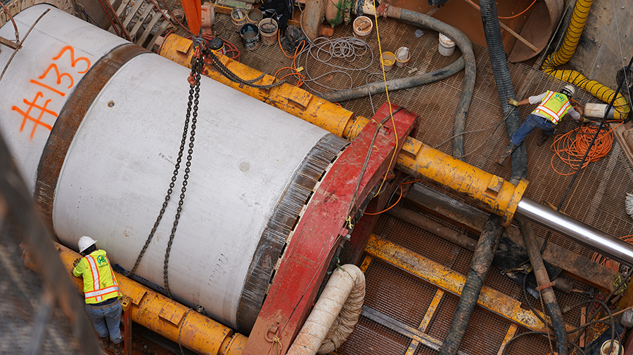  Crew member helps place pipe next to one already in ground