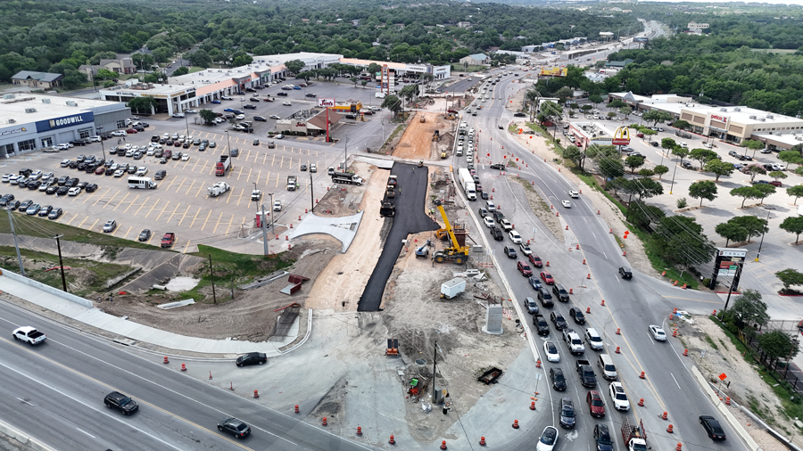 Las cuadrillas de Oak Hill Parkway utilizan una pavimentadora y un rodillo estático de tambor liso para colocar asfalto nuevo a lo largo de una parte de la SH 71 cerca del intercambio "Y". Una vez completados, estos nuevos carriles servirán como la futura carretera de acceso SH 71 en dirección este.  Mayo 2025