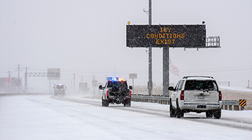 snow and ice covered roads with icy conditions exist signage