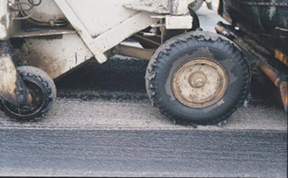 Tack coat tracking resulting in no tackcoat in the wheel path.© Copyright 2006 University of Washington (click in image to see full-size image)