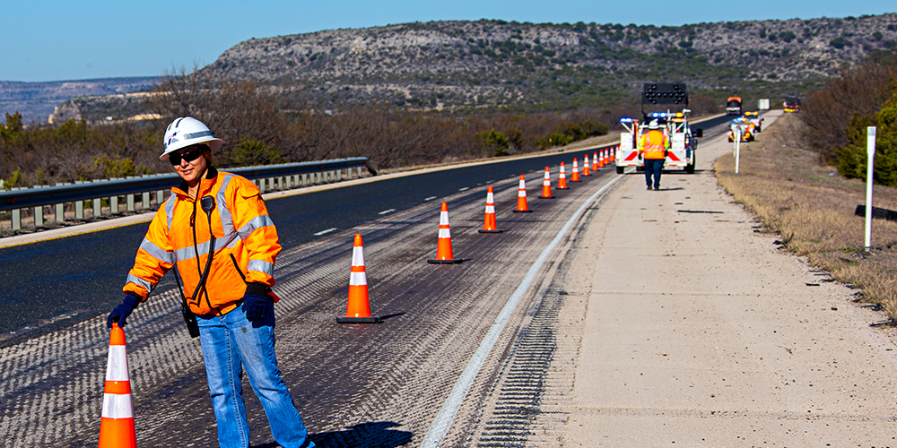TxDOT maintenance road worker placing cones roadside