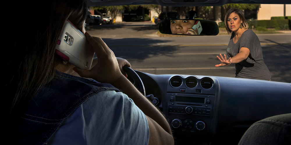 Distracted driver on cell phone approaching woman in crosswalk